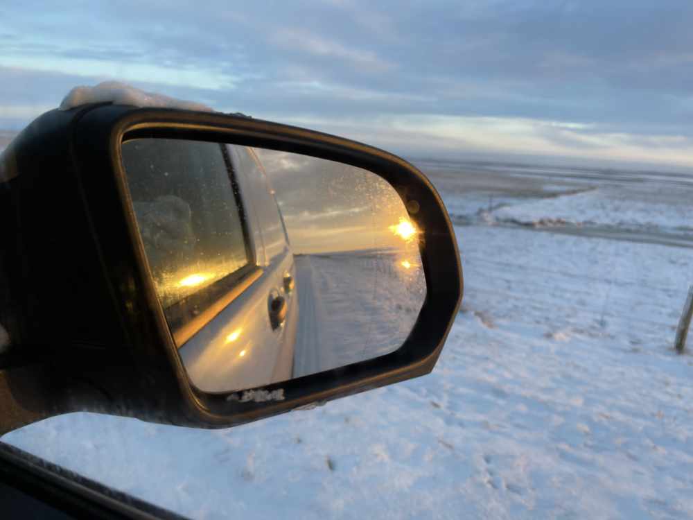 Sonnenuntergang über dem Meer im Außenspiegel des Autos